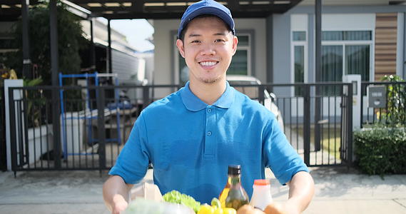 穿着蓝色制服的亚洲人把食物送到接收者顾客面前的商店吃水果和蔬菜视频的预览图