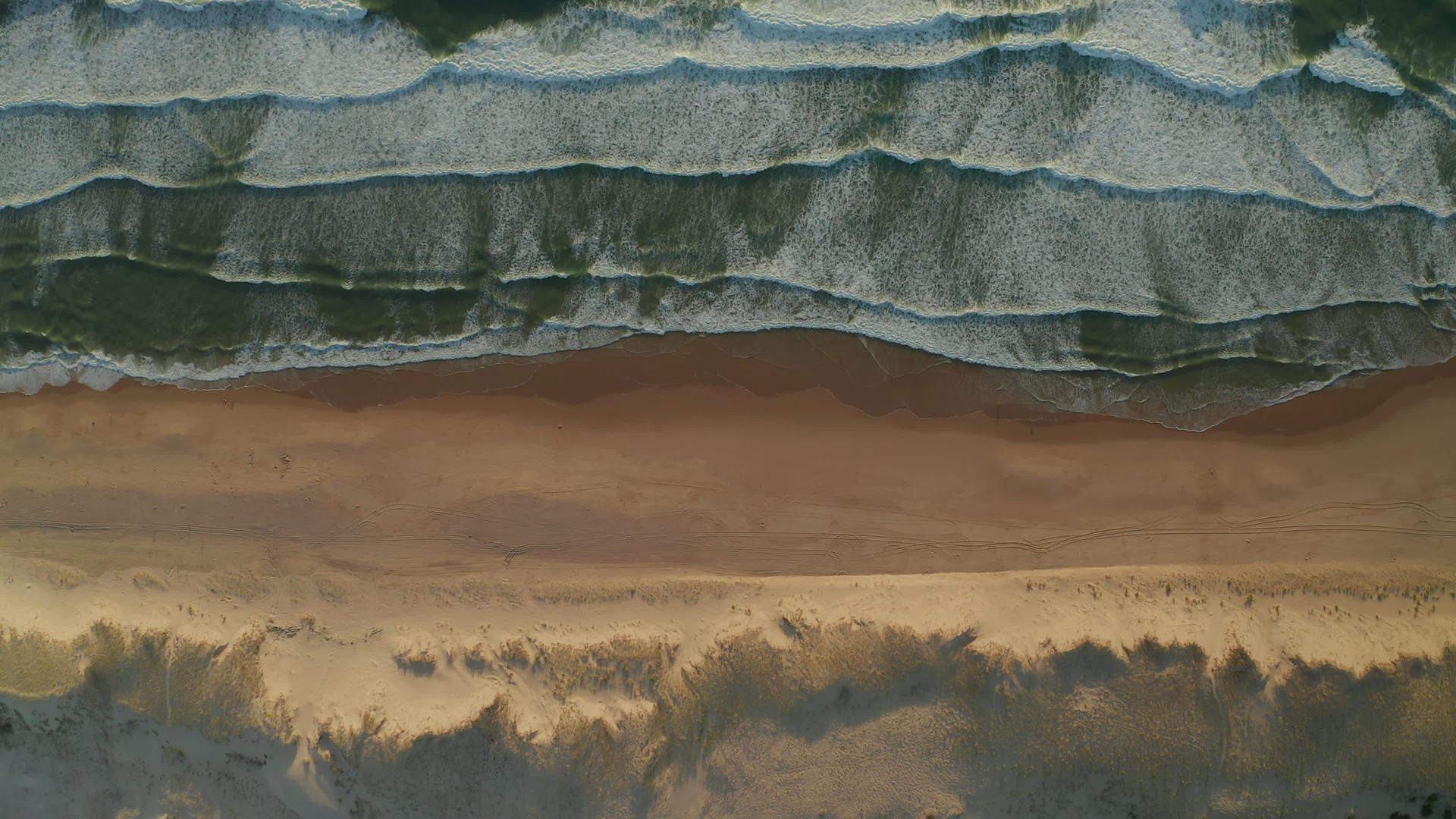 美丽的海滩风景广阔沙丘和海浪在白色泡沫中从上到下落在空中视频的预览图