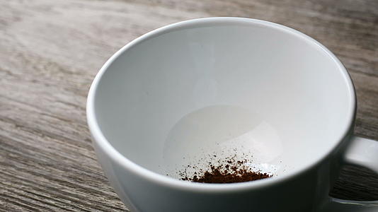 把即时咖啡放在木桌上的杯子里把热水倒进咖啡里视频的预览图