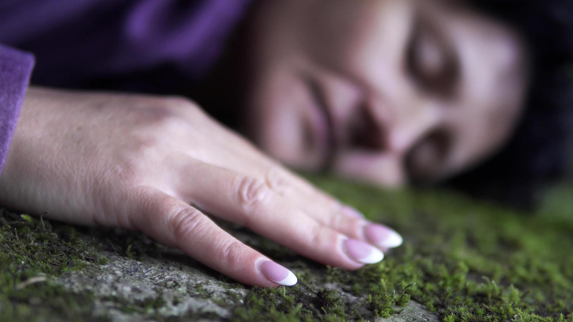 情绪低落的女人躺在草地上一只手轻轻地抚摸着视频的预览图