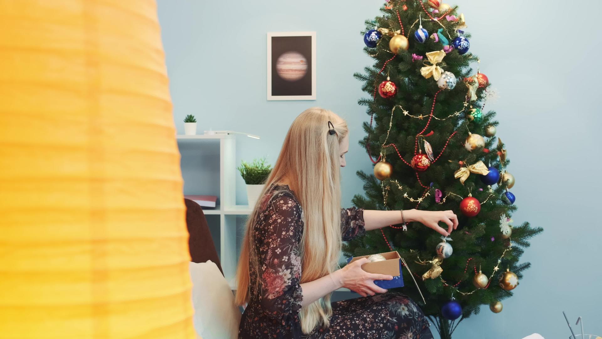 这位美丽的女士在圣诞树上挂着玩具视频的预览图