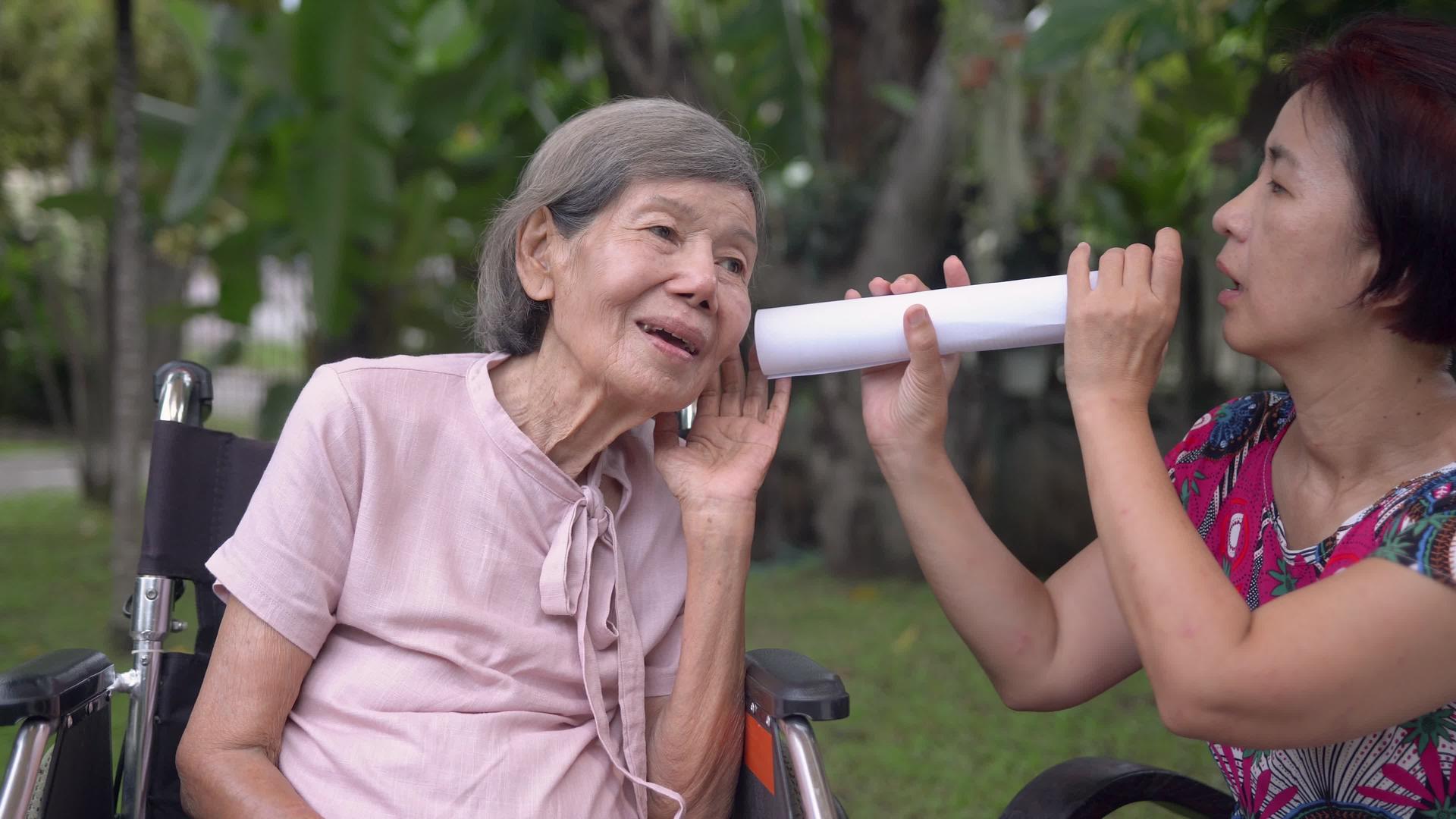女儿用纸管与听力障碍的老年妇女交谈视频的预览图