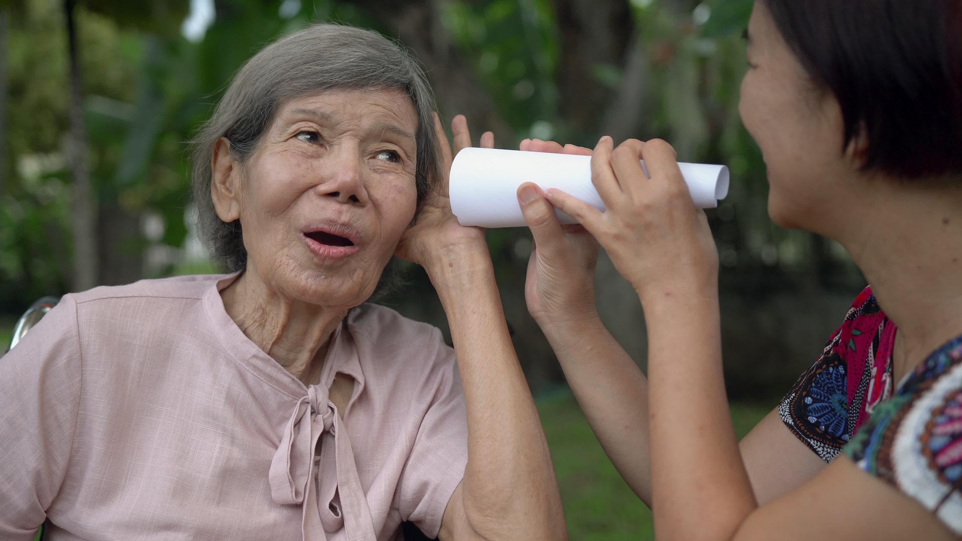 女儿用纸管与听力障碍的老年妇女交谈视频的预览图