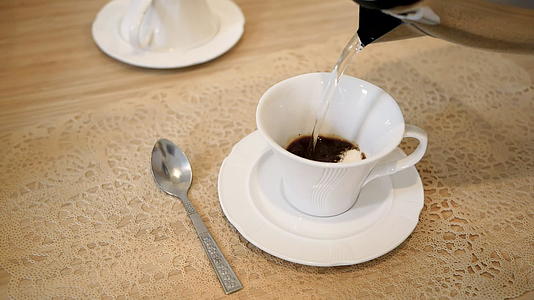在桌子上的一个白色杯子里用勺子搅拌咖啡视频的预览图