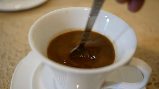 在桌子上的一个白色杯子里用勺子搅拌咖啡视频的预览图
