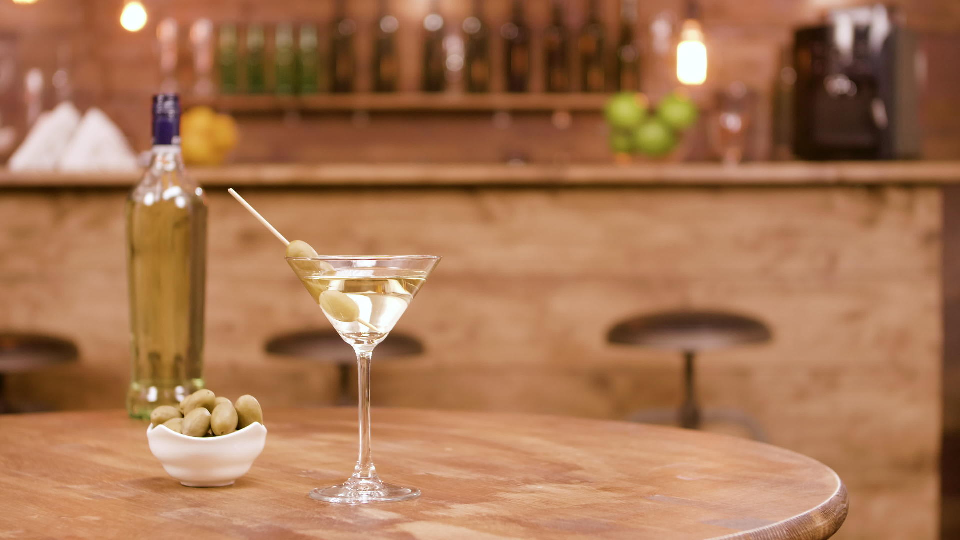 一瓶葡萄酒和一杯马提尼在木桌上加入橄榄视频的预览图