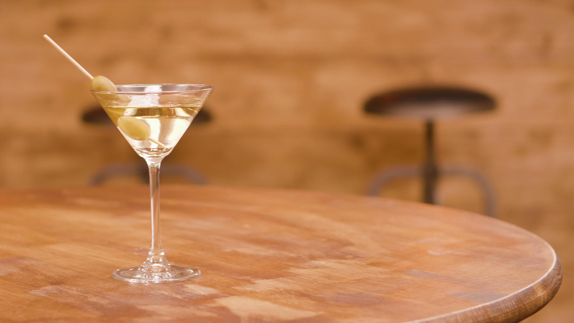 一杯马提尼酒在木桌上加入橄榄视频的预览图