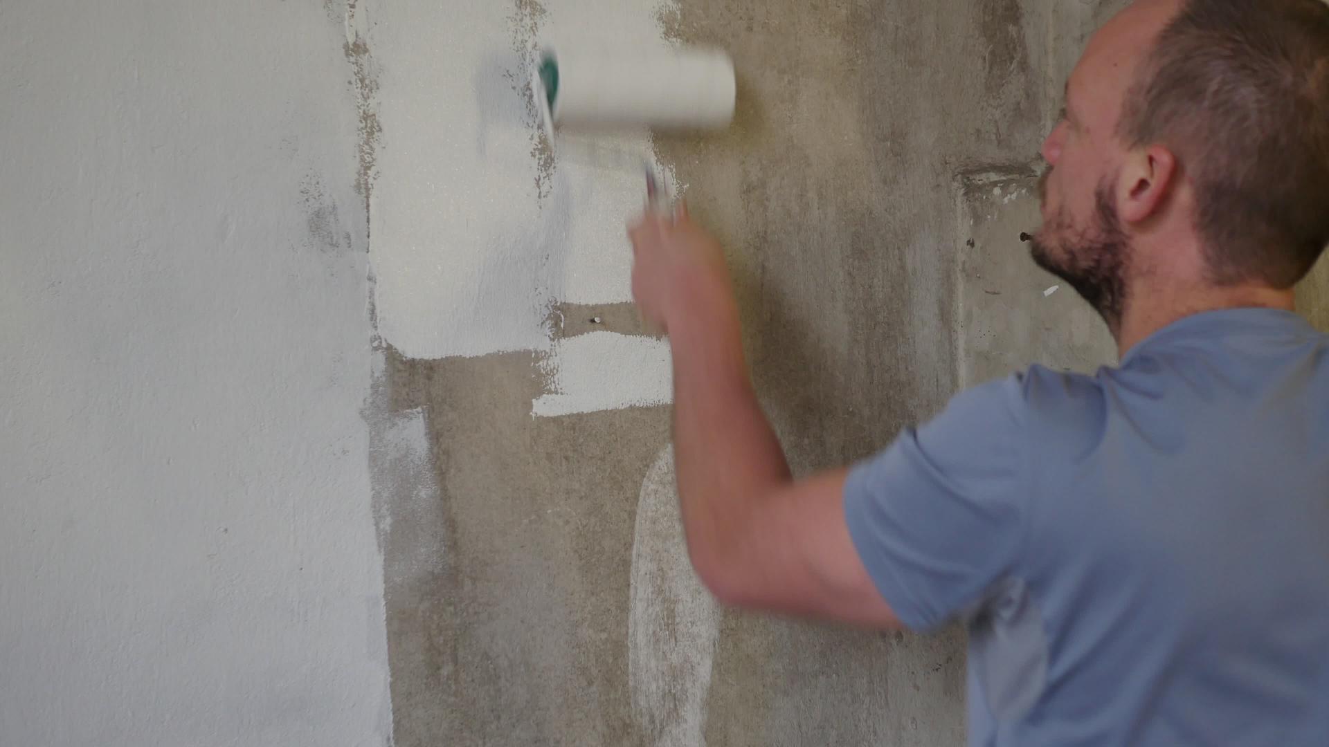 油漆期间墙上的油漆滚筒用白色翻新建筑墙壁英俊年轻视频的预览图