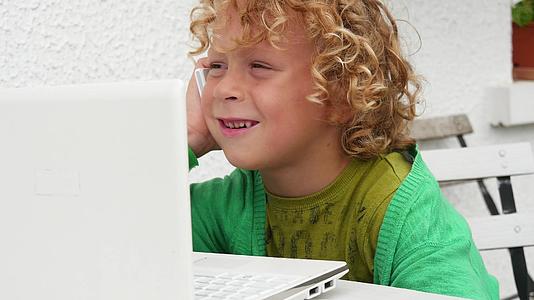金发男孩玩智能手机和笔记本电脑视频的预览图