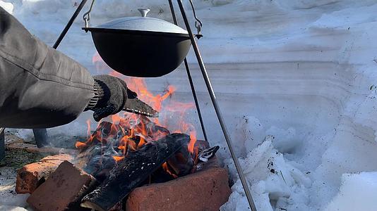 一个旅游锅挂在冬天的火上在冬天用大自然的火做饭视频的预览图