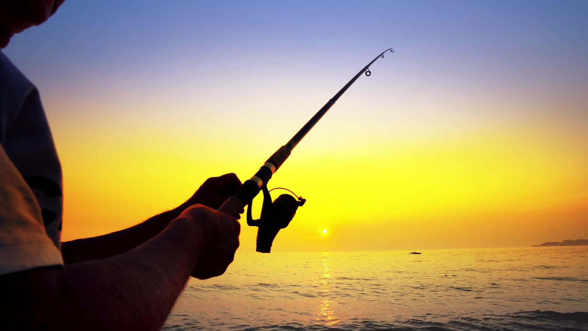 在金色的阳光下用美丽的海洋捕鱼的渔民视频的预览图