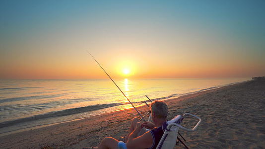 日落时在海滩上钓鱼的渔民视频的预览图