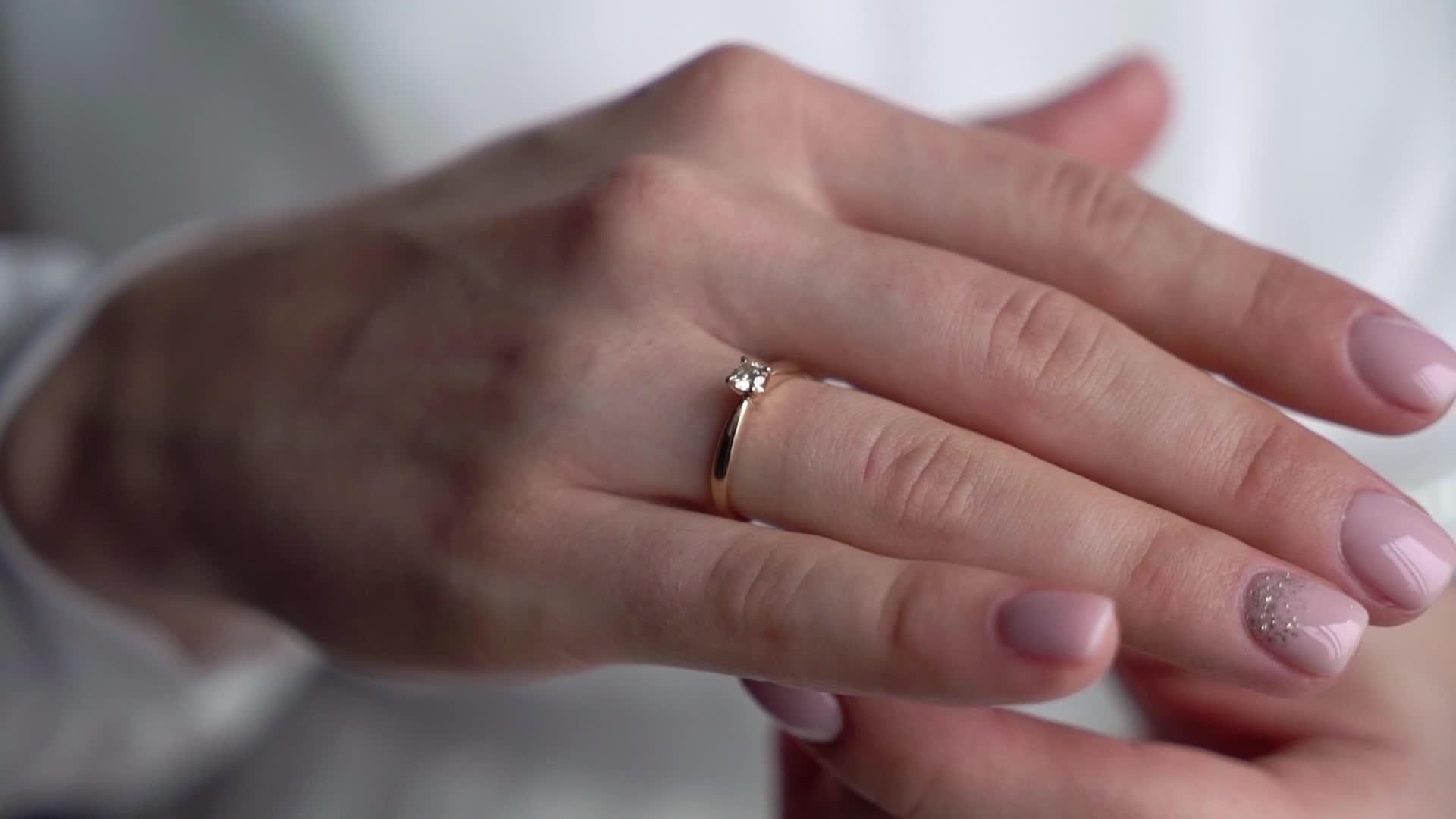 这位年轻女子戴着她的手指珠宝戒指戴着钻石豪华而昂贵的求婚戒指视频的预览图