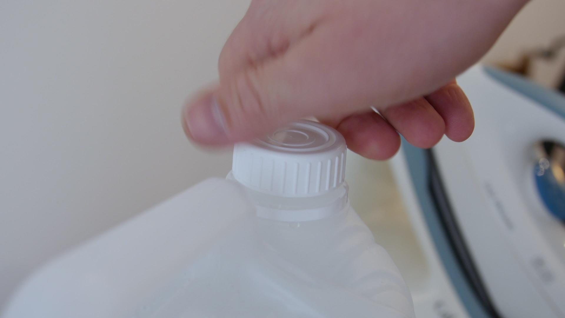 男子在专业熨烫过程中打开一瓶软化水去离子水去离子水视频的预览图
