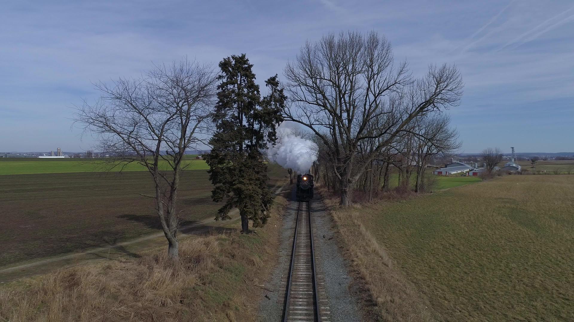 修好的蒸汽机车和公共汽车的鸟瞰图穿过火车前的农田视频的预览图