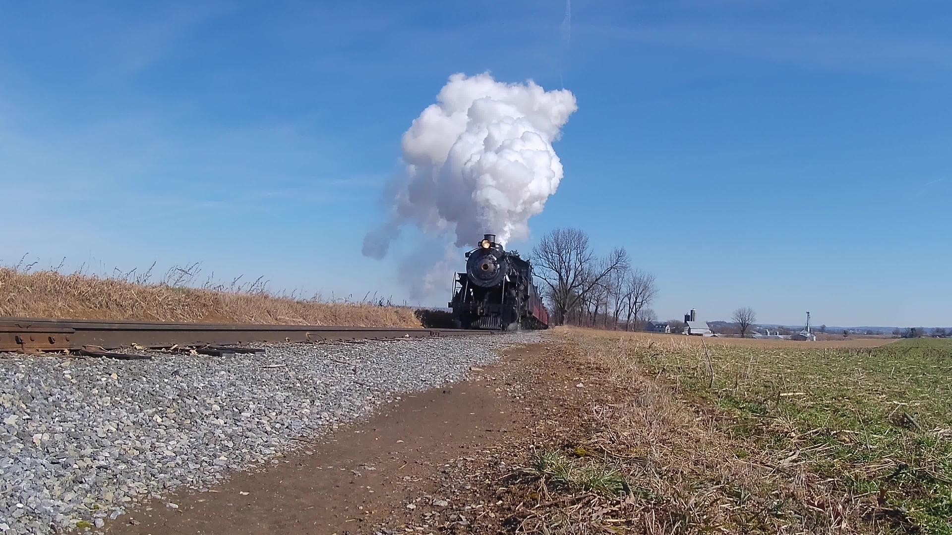 修好的蒸汽机车和公共汽车在火车前穿过农场和村庄视频的预览图