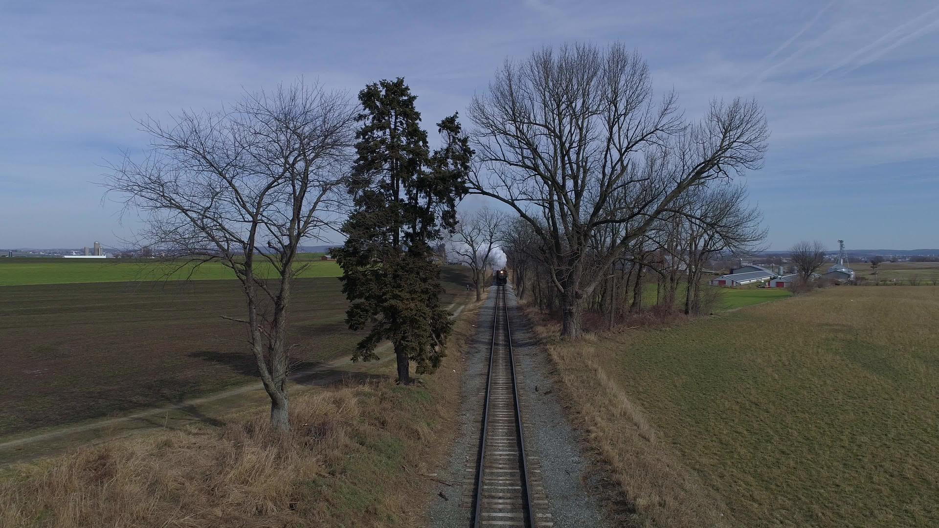 修好的蒸汽机车和公共汽车的鸟瞰图穿过火车前的乡村视频的预览图
