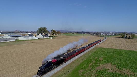 古老的恢复蒸汽机车和乘用车在农村汽车之间的空气中视频的预览图