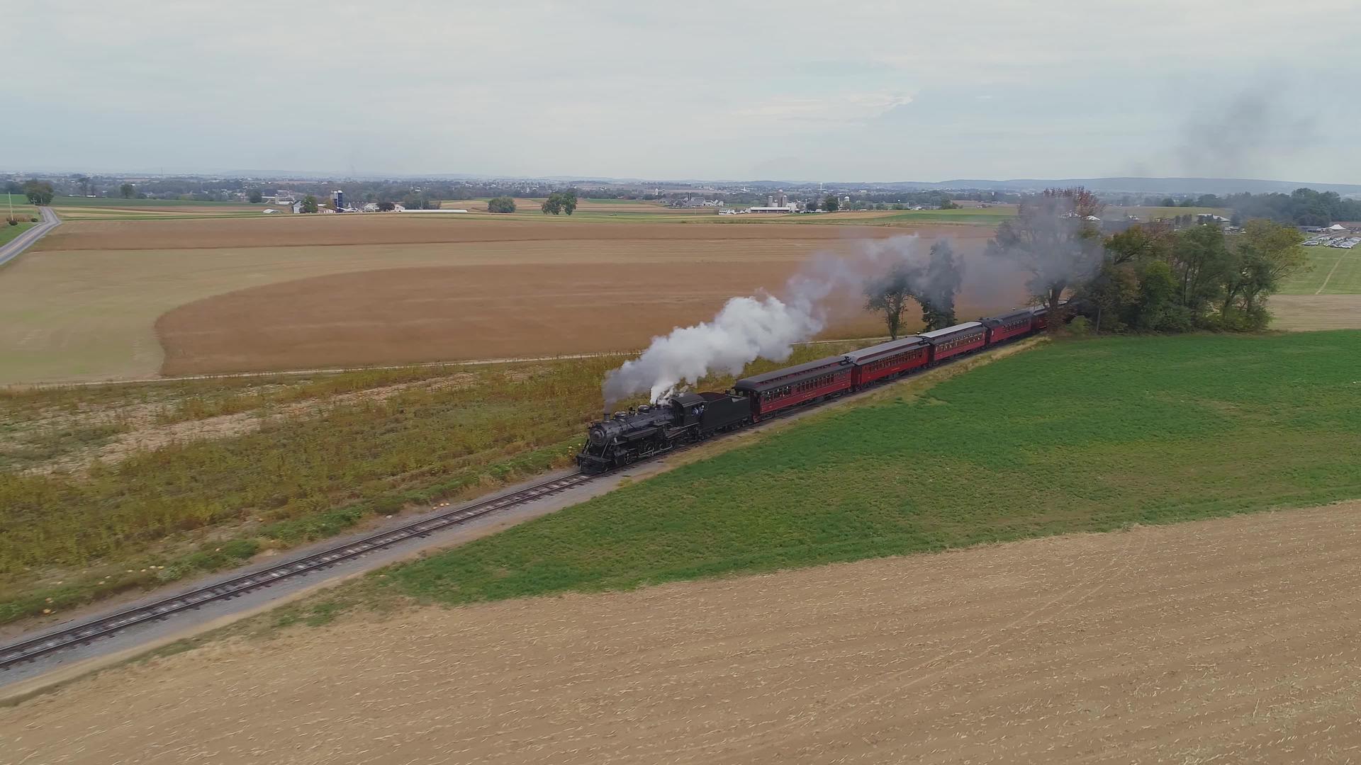 从角度来看一台恢复的蒸汽机将一辆古老的公共汽车拖到农田视频的预览图
