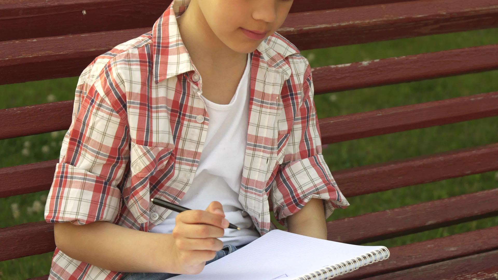 小男孩在长凳上画笔记本视频的预览图