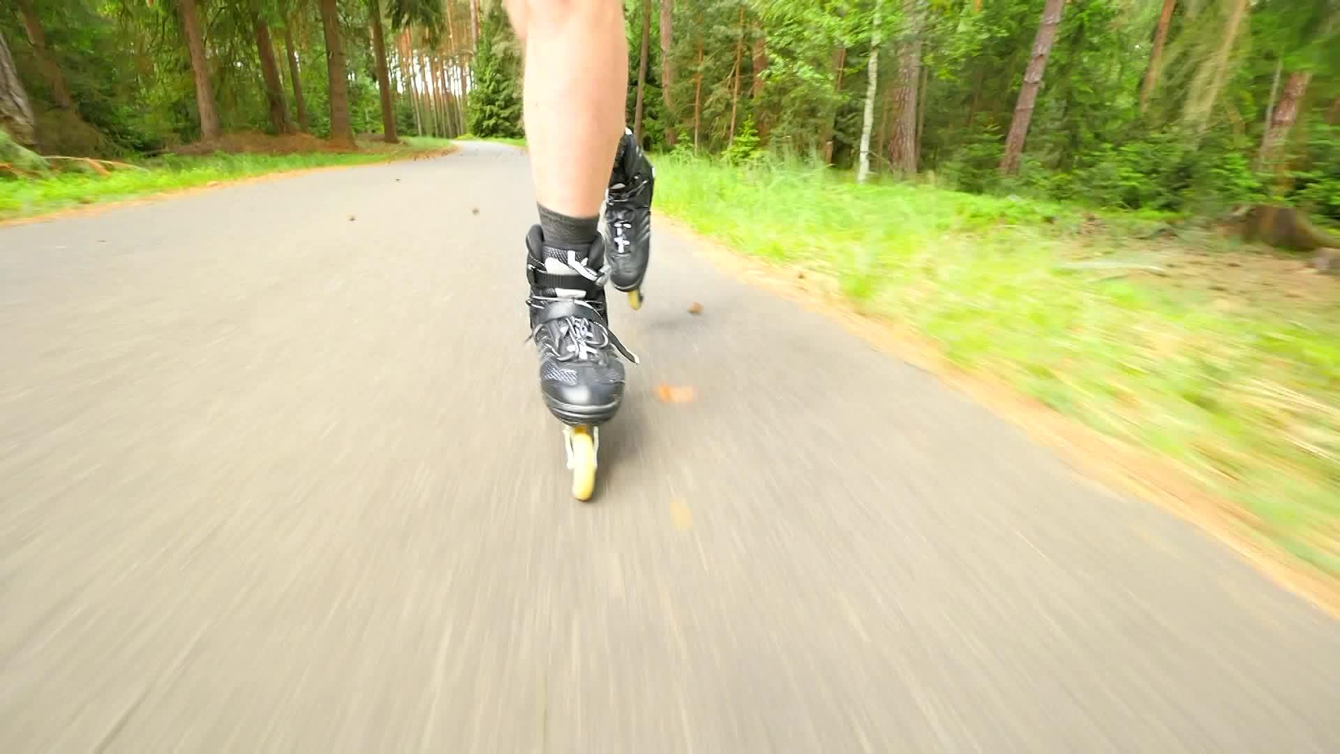 在炎热的夏天在松树林里随机滑动轮滑在沥青上滑冰视频的预览图