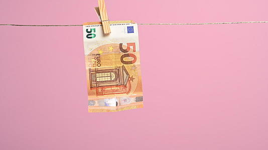 女性手挂在衣服线纸上欧元联盟50欧元粉色背景洗钱视频的预览图