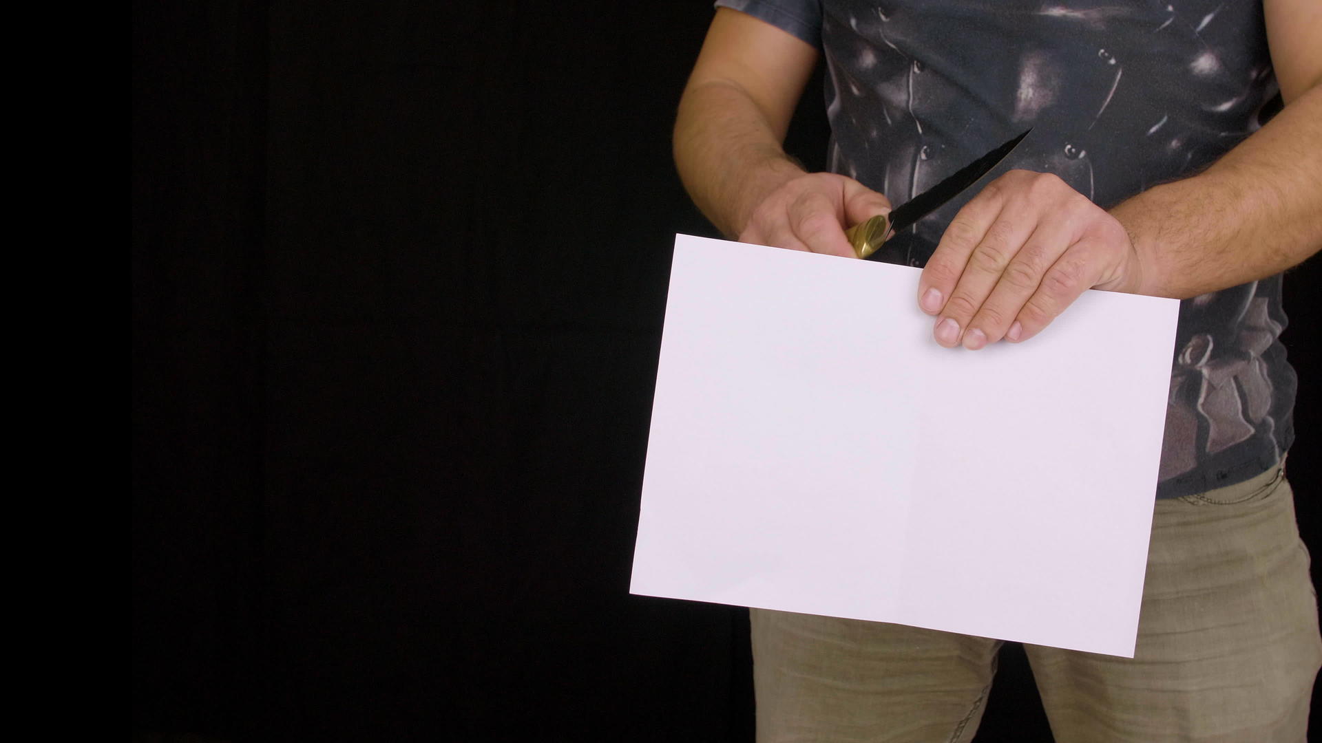 男人手里拿着刀用黑色背景纸上的黑色纸测试刀片视频的预览图