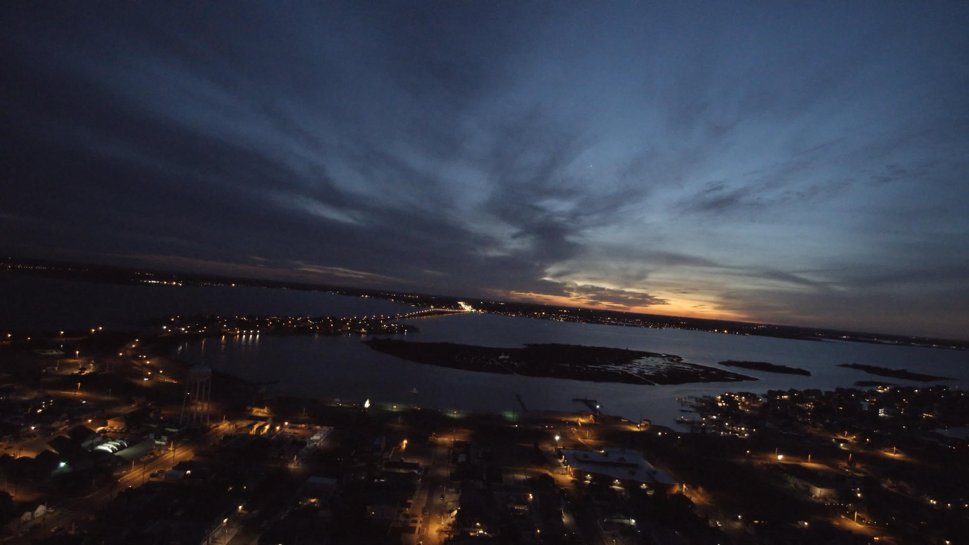 日落和全景观光照亮了小村镇的海湾无人驾驶飞机在夜间飞行视频的预览图