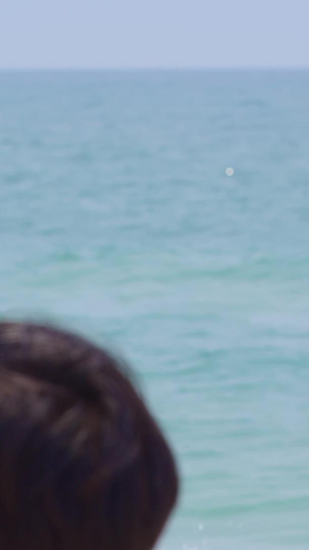 在海边喝水的男青年背影视频的预览图