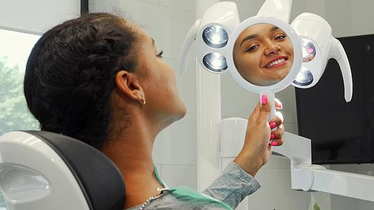 快乐的非洲女人在镜子里看着她健康的微笑视频的预览图
