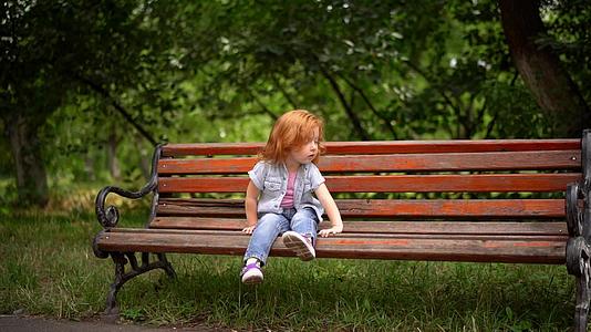 可爱的小女孩坐在长凳上视频的预览图