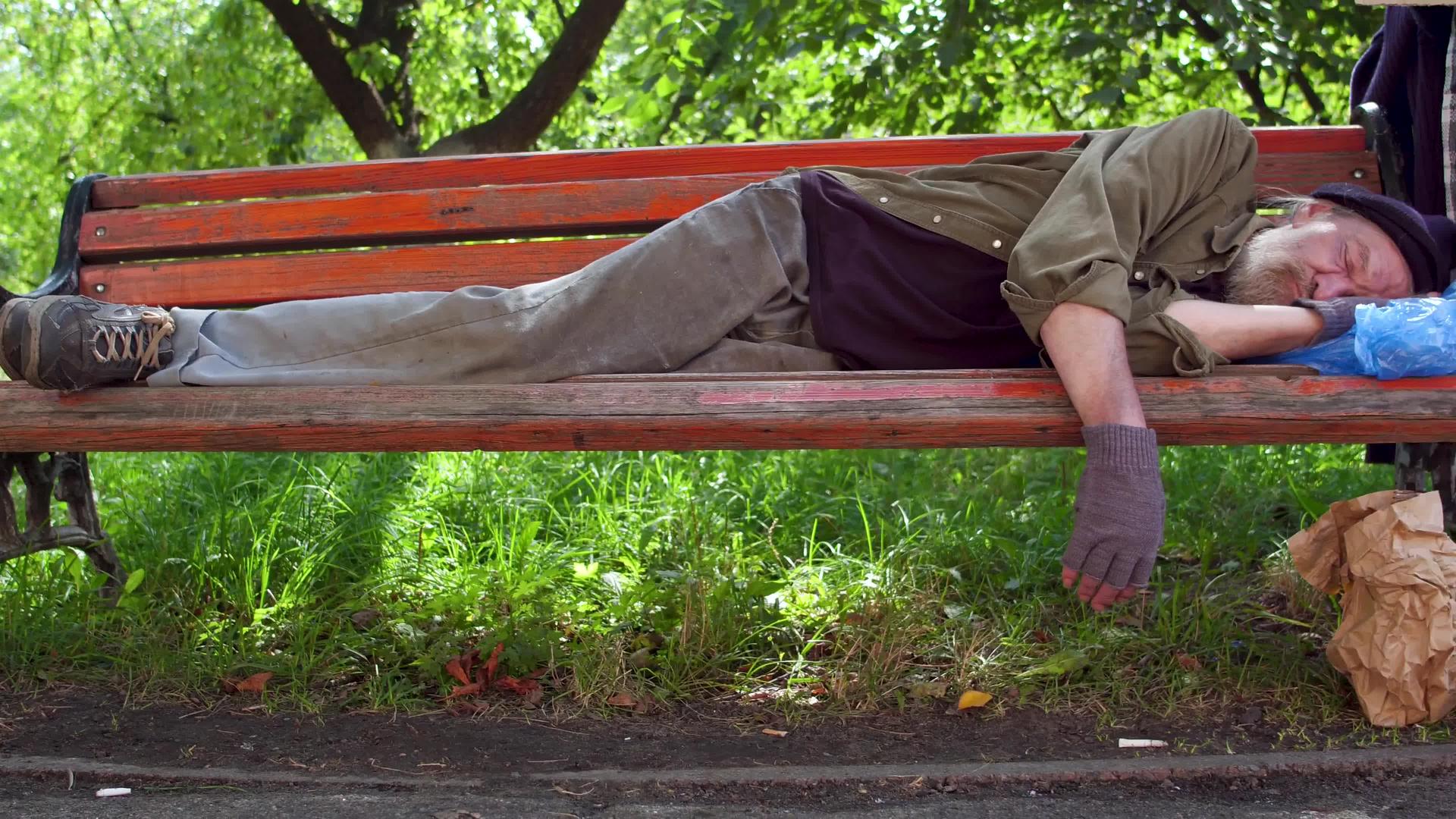 醉汉无家可归的男人白天睡在街上的长椅上视频的预览图