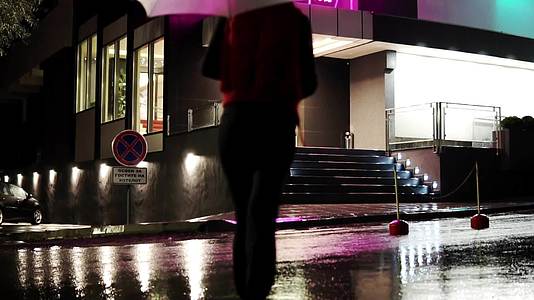 晚上走在彩色雨伞下的女人在门前溜走了视频的预览图