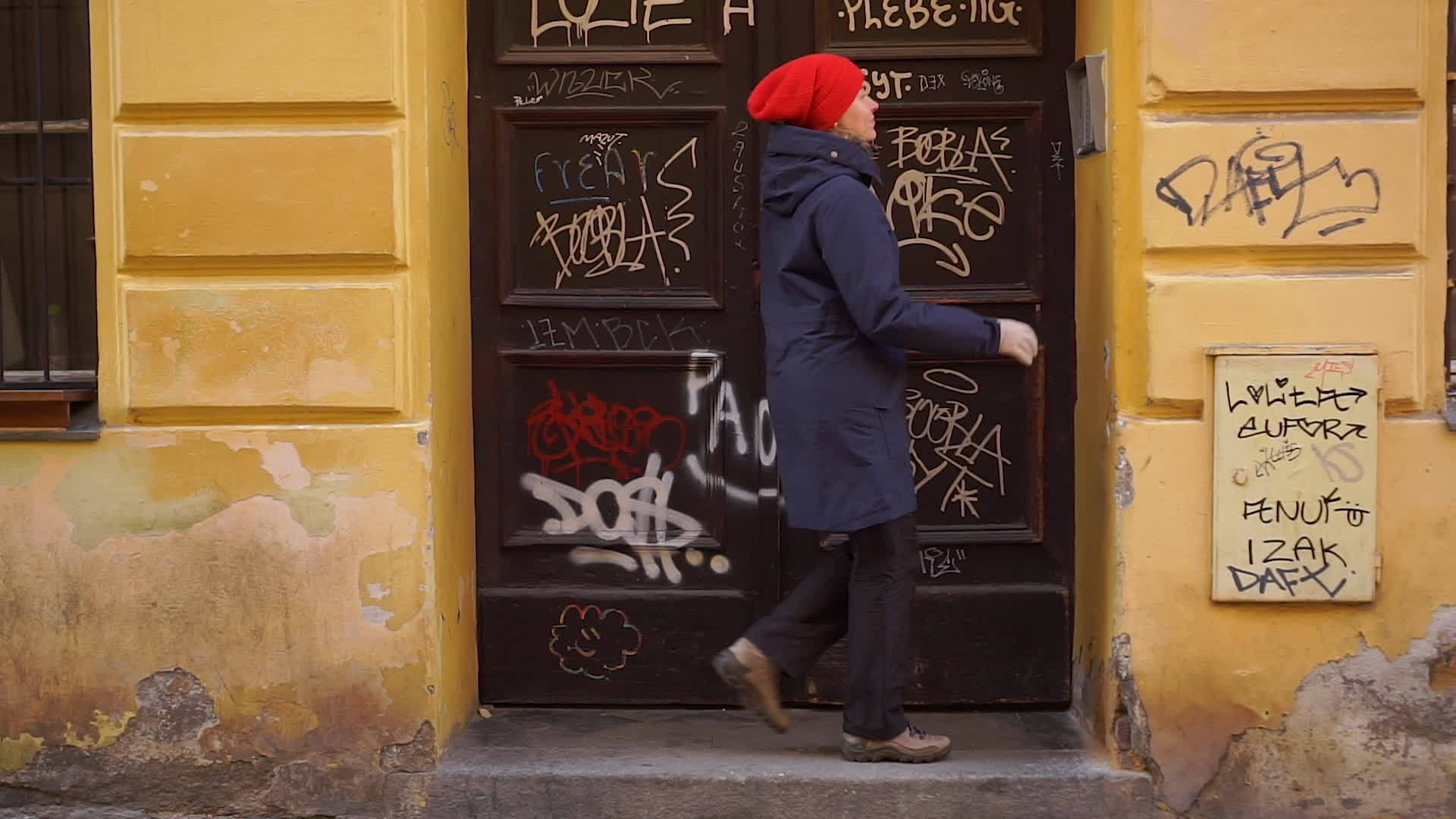 红帽女人敲门铃旧欧洲街的门涂鸦视频的预览图