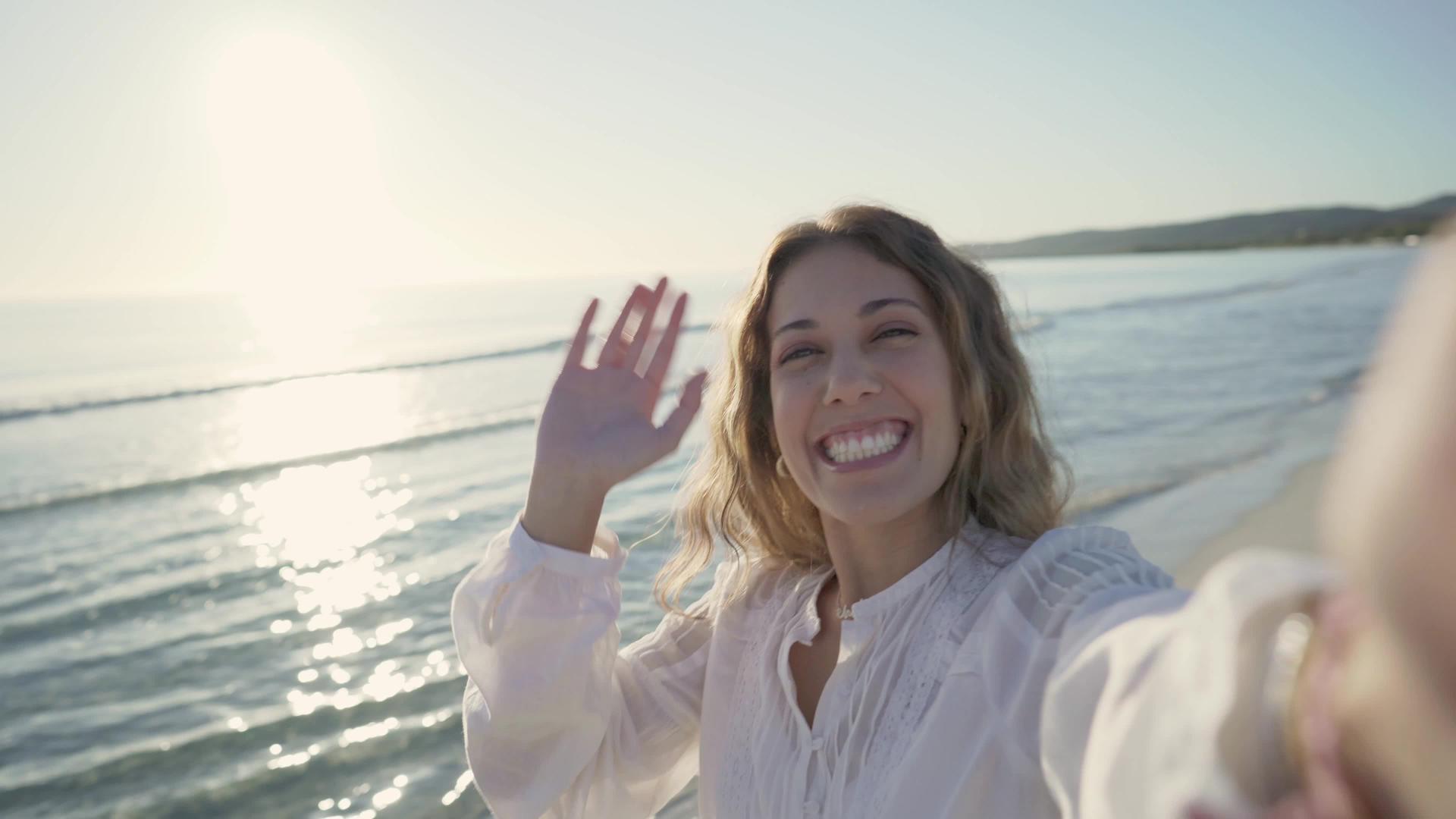 在日落或黎明时穿着白衬衫的年轻美女被围在热带海滩上视频的预览图