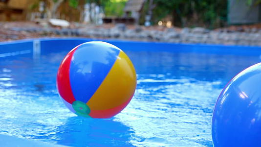彩色海滩球被扔进游泳池的水中视频的预览图