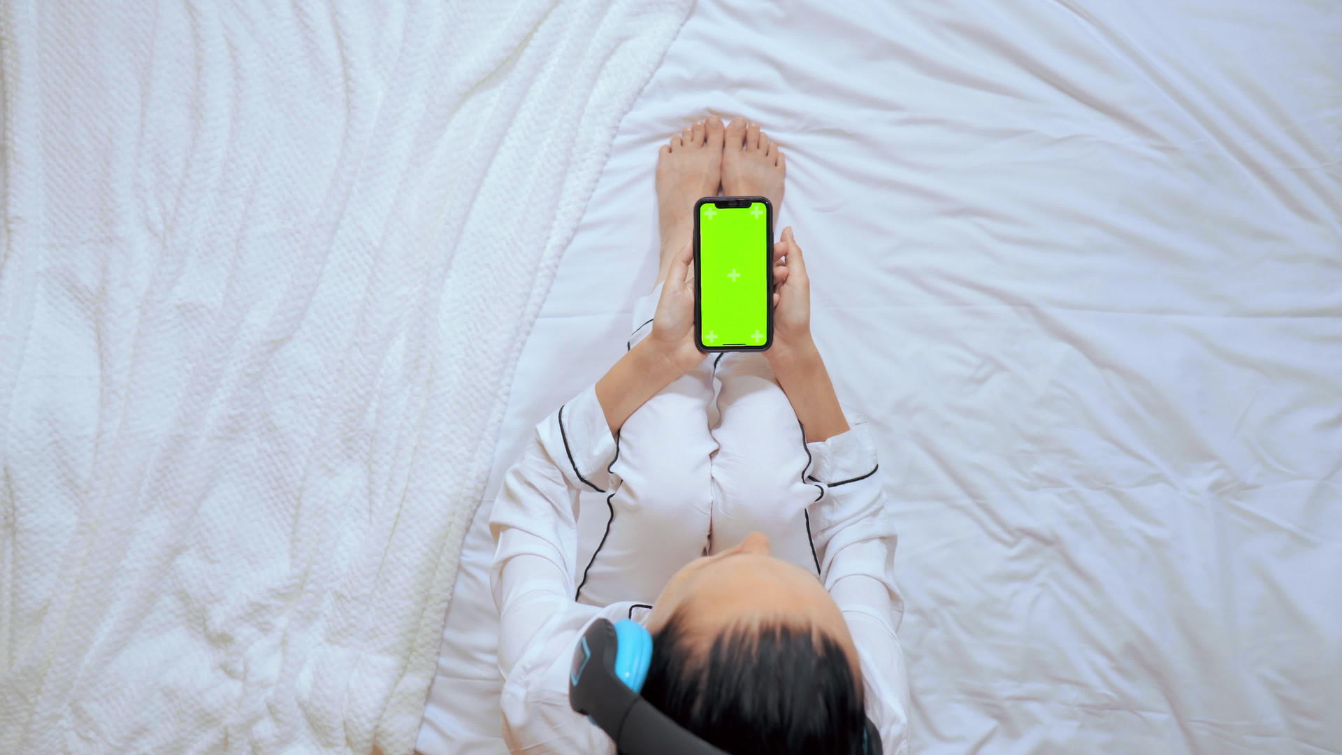 坐在床上女人拿着智能手机在上面看着视频的预览图