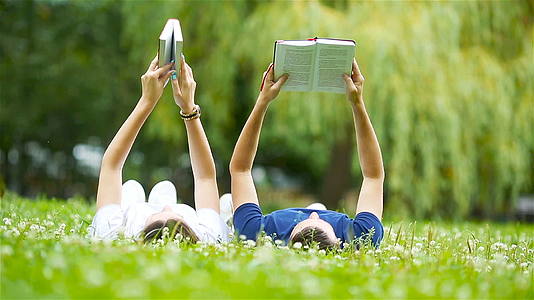 一对学生情侣躺在草地上看书视频的预览图
