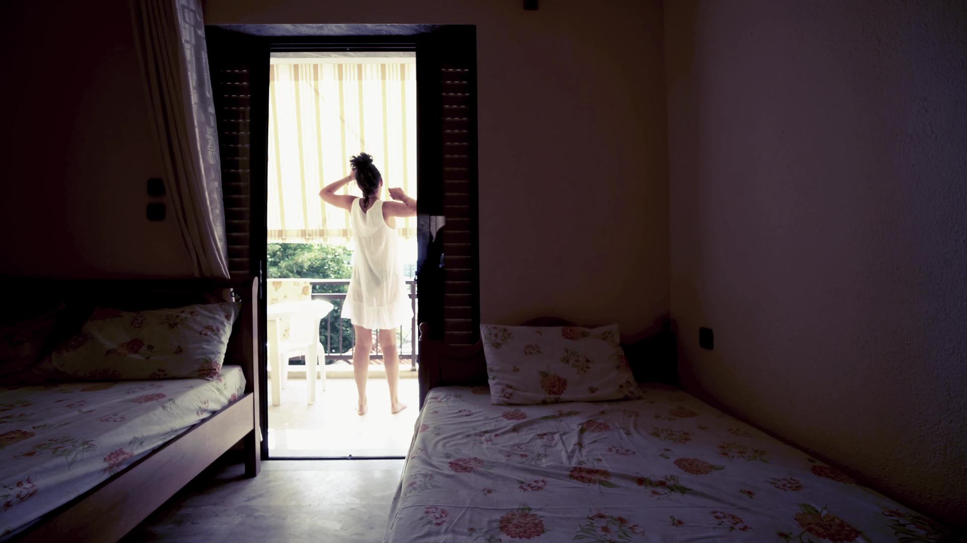 快乐放松的亚洲女性在早上伸展双臂在卧室阳台上度假视频的预览图