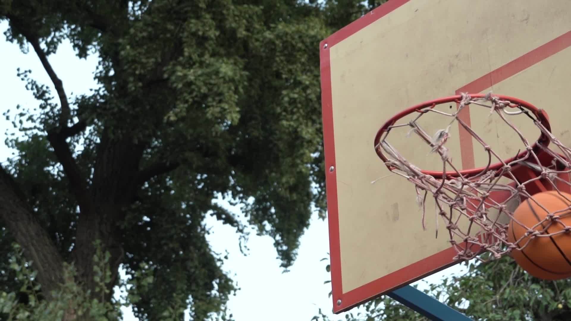 橙色篮球在公园的街头法庭上击中篮子达到目标视频的预览图