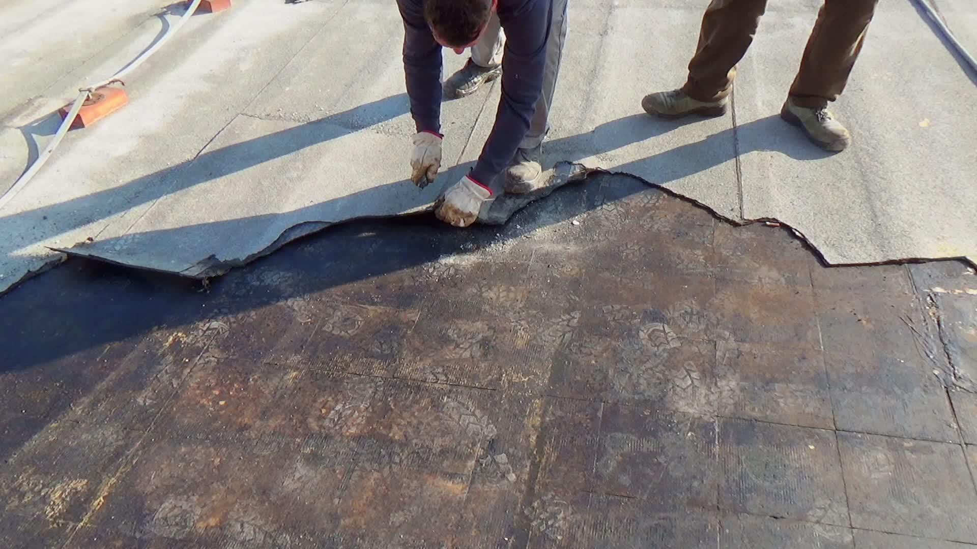 工人从建筑物的平屋顶上移除受损的沥青层视频的预览图