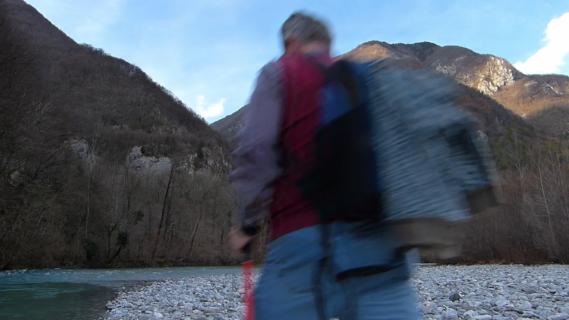 大约60岁的男子在河边徒步旅行在山脉的背景下视频的预览图