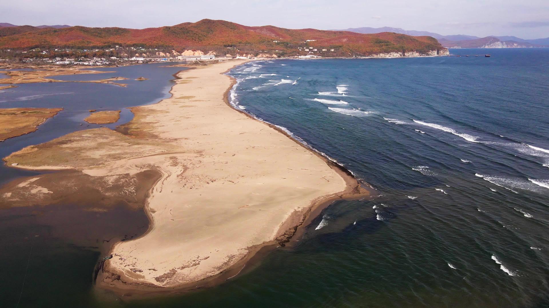 摄像机飞过一个覆盖着蓝色海浪的宽阔沙滩视频的预览图