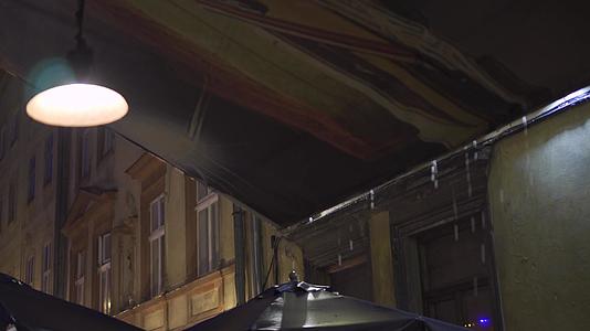 晚上雨中的户外街头咖啡馆的雨滴从屋檐上落下挂着灯笼视频的预览图