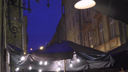 夜里大雨中的户外街头咖啡馆的雨滴从树冠上掉了下来灯笼挂灯笼上视频的预览图