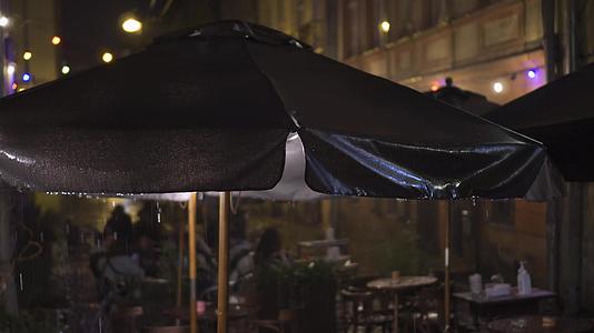 户外老城街咖啡馆的雨夜在倾盆大雨中湿漉漉的树冠和水滴视频的预览图