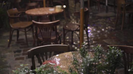 街头咖啡馆的湿木家具桌椅在夜晚的大雨中落在桌子上视频的预览图
