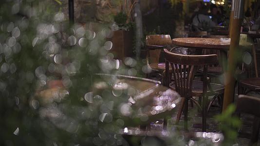 街头咖啡馆湿木家具桌椅背景在夜间大雨中难以辨认视频的预览图