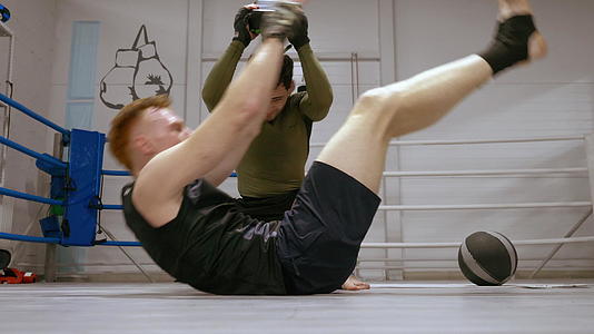 个人训练拳击手和他的教练一起做腹部运动视频的预览图