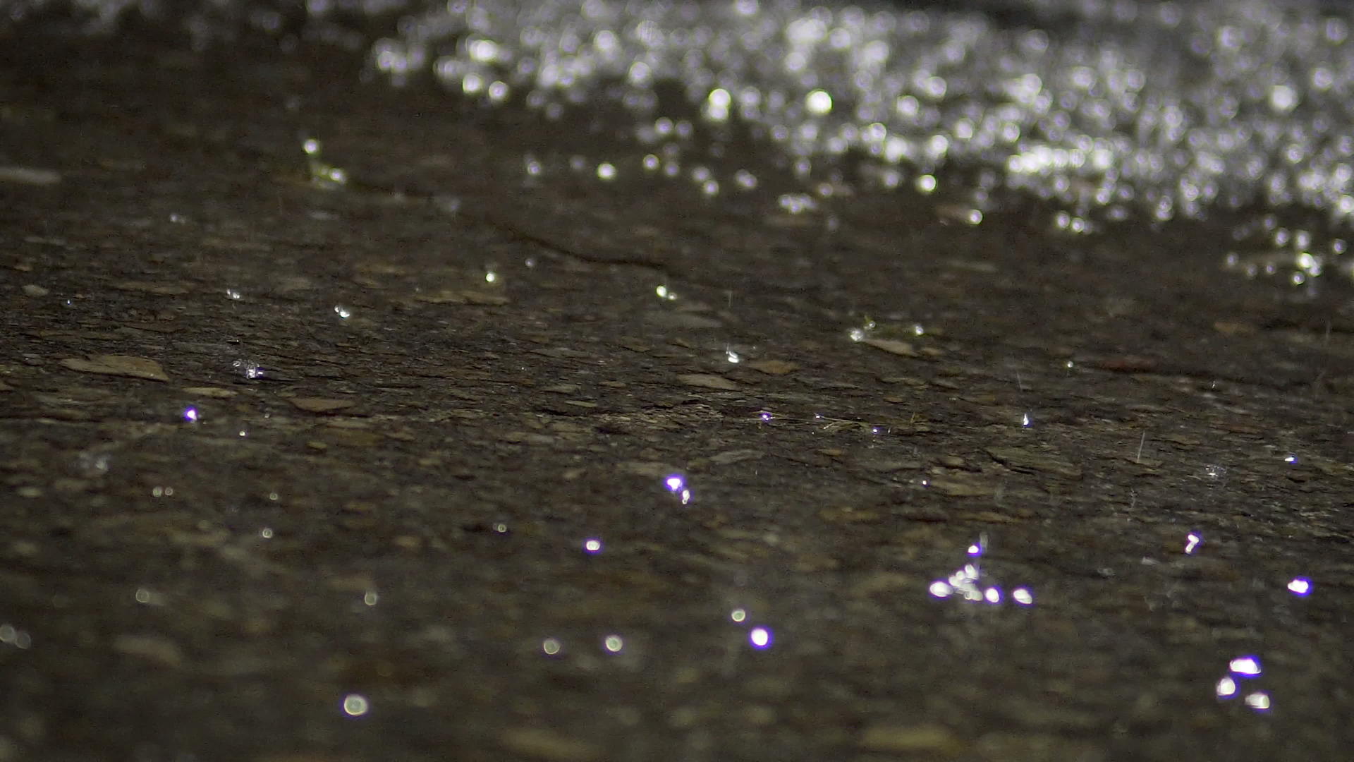 晚上城市人行道上的一个水坑里下了大雨有光反射电影回灌视频的预览图